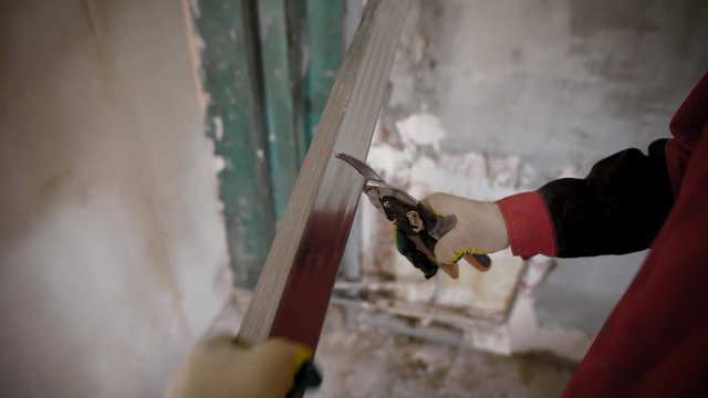 Construction worker uses metall cutting scissors to cut metall drywall profiles.