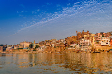 Fototapeta premium A view from River Ganges of Old Historical Varanasi city with weathered buildings at the time of Sunrise