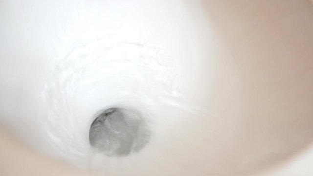 Old Toilet flushes and clean water drops into bowl during flush cycle