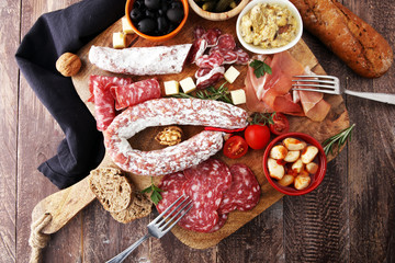 Italian antipasti wine snacks variety set. Cheese, Mediterranean olives, pickles, Prosciutto di Parma, tomatoes, artichokes and wine in glasses. Spanish tapas.