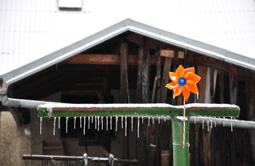 Orange children's propeller with icicles on a green column.