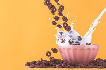 Chocolate cereals milk bowl splash on yellow back ground, left space.