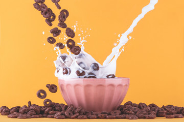 Chocolate cereals milk bowl splash on yellow back ground, centered.