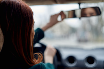 A woman fixing a mirror in the car