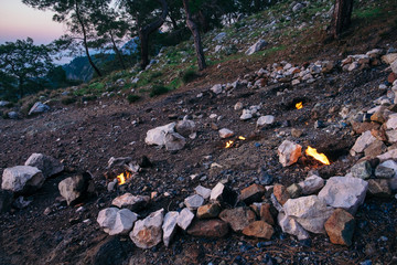 Chimeara's flames among the rocks next to green grass and trees