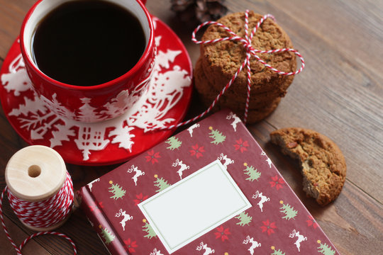 Red Christmas mug with coffee and cookies on the wooden table