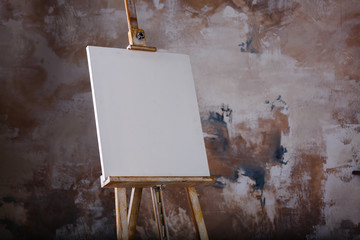 White empty artistic canvas on an easel for drawing images by an artist on a gray background