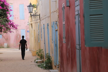 Silhouette of a lonely man walking in a narrow colored street of goree island in senegal