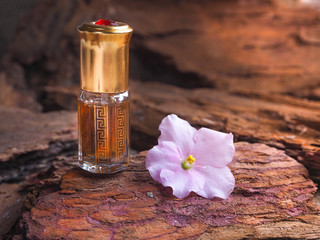 Bottle of oil agarwood tree against the bark. Arabian oud attar perfume or agarwood oil fragrances...