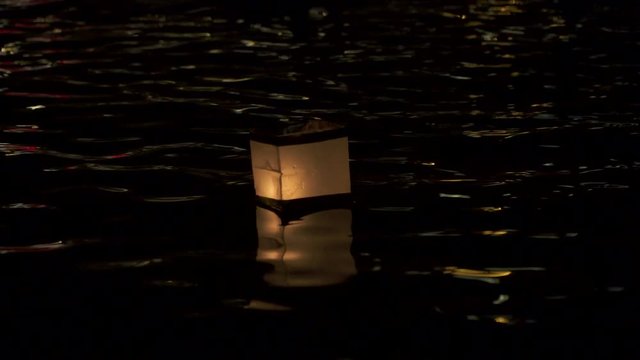 The light of paper lanterns floating on the water of Vltava illuminating the dark of Prague