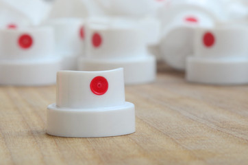 Several new plastic nozzles from a paint sprayer that lie on a wooden surface against a gray wall background. The concept of street art and graffiti © mehaniq41