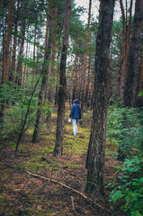 Young single woman walking among trees in the forest alone