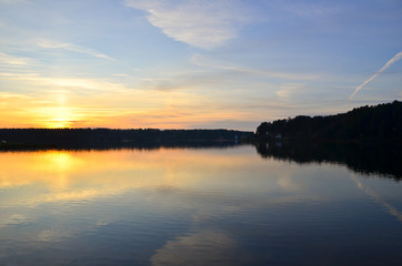 Beautiful orange sunset over the lake with sky reflected in the water