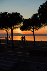 Tranquil Scene of People Walking and Biking by the sea, after sunset time