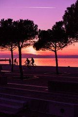 Tranquil Scene of People Walking and Biking by the sea, after sunset time, purple tones