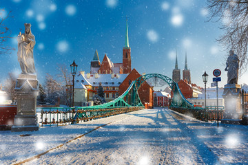 Fototapeta premium Tumski Bridge and Island with Cathedral of St. John and church of the Holy Cross and St. Bartholomew in the snowy overcast winter day in Wroclaw, Poland