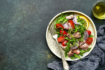 Tuna salad with cherry tomatoes,arugula leaves and red onion.Top view with copy space.