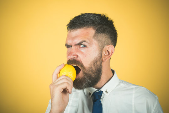 man with long beard eat lemon fruit on yellow background