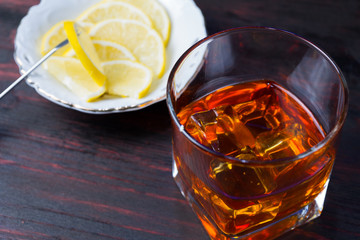 A glass of alcohol and sliced lemon.