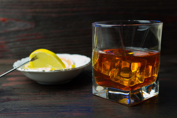 A glass of alcohol and sliced lemon.