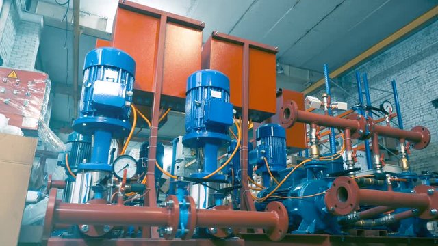 Low angle shot of a number of new water pumps before a large-scale assembly in a factory interior