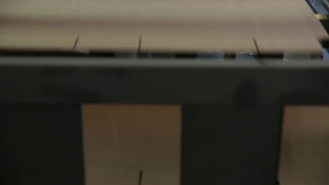 Closeup image of pleat cardboard row at factory background. Manufacture of cardboard boxes. Footage with sound.