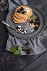 Healthy breakfast. Belgian waffles with wild blackberries and cream cheese in dark background