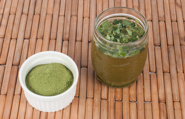 Moringa leaves with juice in a glass on wooden background