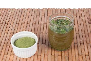 Moringa leaves with juice in a glass on wooden background