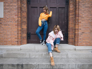 Two fashion Chinese girls making poses in front of a retro style wooden door in Shanghai bund.