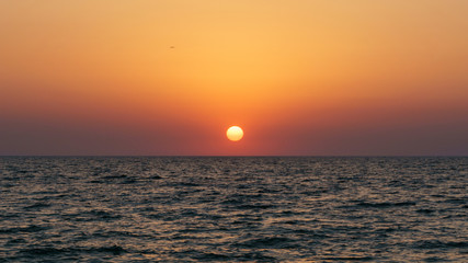 Sunset on the sea in clear weather with the sun disk