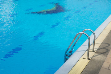 Grab bars ladder in the blue swimming pool. Concept Healthy exercise.