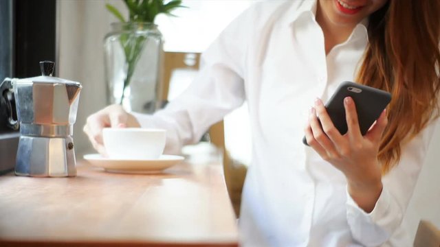 Businesswoman use mobile phone and drink coffee on wooden table. Asian woman using phone and cup of coffee. Freelancer working in coffee shop. Woking outside office lifestyle.