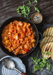 Coconut milk vegetable curry sauce and grilled bread on dark background, top view. Delicious vegetarian food concept