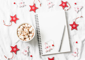 Hot chocolate with marshmallows and cinnamon, clean blank notepad, christmas decorations on a light background. Christmas inspiration planning background