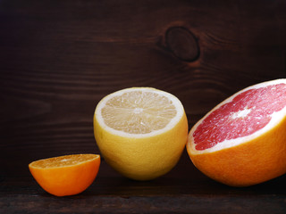 Lemon, mandarin and grapefruit in a cut on a wooden background. Still-life with fruit.