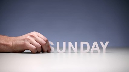Male hand composition word sunday on table background. Day in week for rest