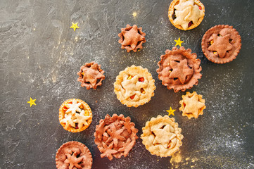 Naklejka premium Different sizes of traditional Christmas dessert - Mince pies. Vanilla and chocolate pastry. Black backdrop.Top view.