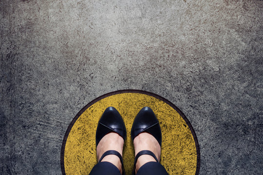 Comfort Zone Concept, Woman with leather shoes Standing inside a Circle Bound, Top view and Dark tone, Grunge Dirty Concrete Floor as Background