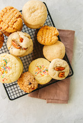 Set of festive cookies on a wire rack. Peanut butter, pecan, oatmeal, shortbread, snickerdoodle round biscuits. Top view. White stone background with copy space.