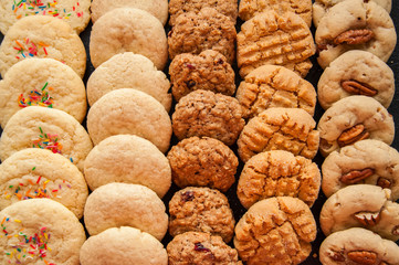 Set of various american style cookies on a black stone background. Shortbread with confetti, snickerdoodle, peanut butter, oatmeal and pecan cookies.