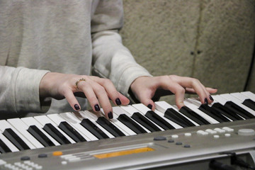 A young girl pianist plays the electronic piano with her favorite music. Female graceful hands touch the keys of the synthesizer close-up.