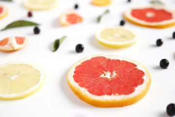 Slices of grapefruit, lemons and tangerines on a white background.