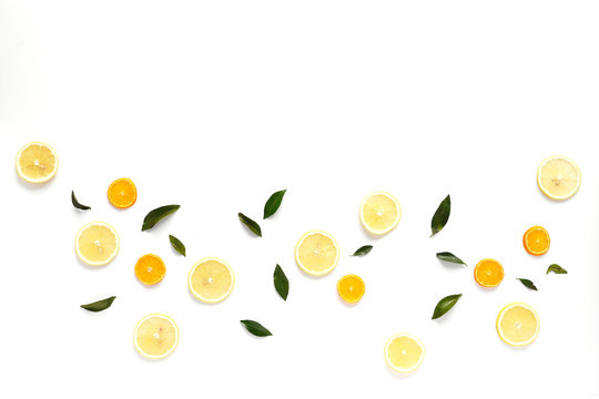 Pattern of fresh fruits on a white background, top view, flat lay.   Composition of green leaves and slices of citrus fruits: lemon, mandarin. Healthy food background, wallpaper, collage.