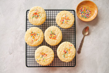 American style round cookies with confetti (shortbread) on a wire rack on a grey stone backdrop.