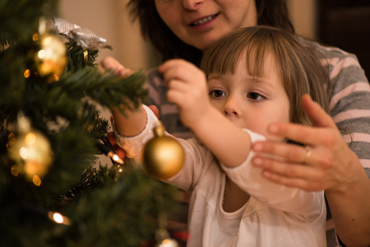 Mother helping her daughter decorate xmas tree