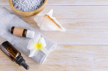 Blue spa sea salt en wooden bowl, lavender essential oil, natural shell and blue towel with exotic flower on wood background. Concept to spa and wellness. Copy space.