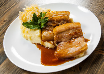 Fried pork chop, mashed potato and vegetable salad in plate on a wooden background.