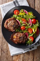 Spicy roasted lamb steak and radish salad, tomato and lettuce close-up. Vertical top view