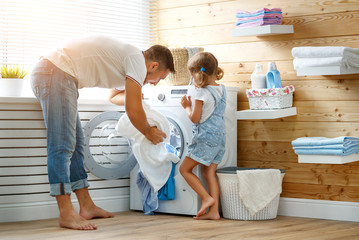 Happy family man father householder and child   in laundry with washing machine .